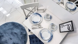 A dining area with a white table set for four, including plates, cutlery, and a cup. - Charming Studio in a Historic Bucharest Courtyard (București)