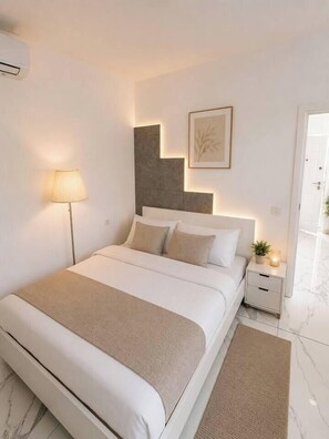 A modern bedroom with a bed, bedside table, lamp, and a framed picture on the wall. - Boutique 1-Bedroom Apartment with Designer Accent (București)