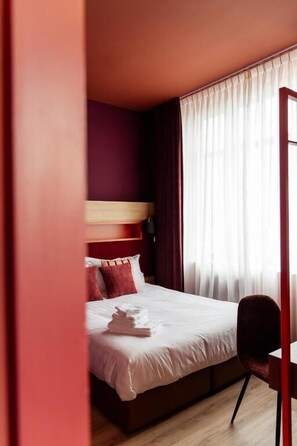 Ein Schlafzimmer mit einem Bett, einem Sessel und einem fenster mit Vorhängen.