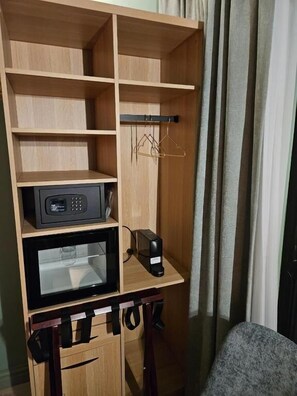 Un armario de madera con varios estantes y un microondas en el estante inferior.