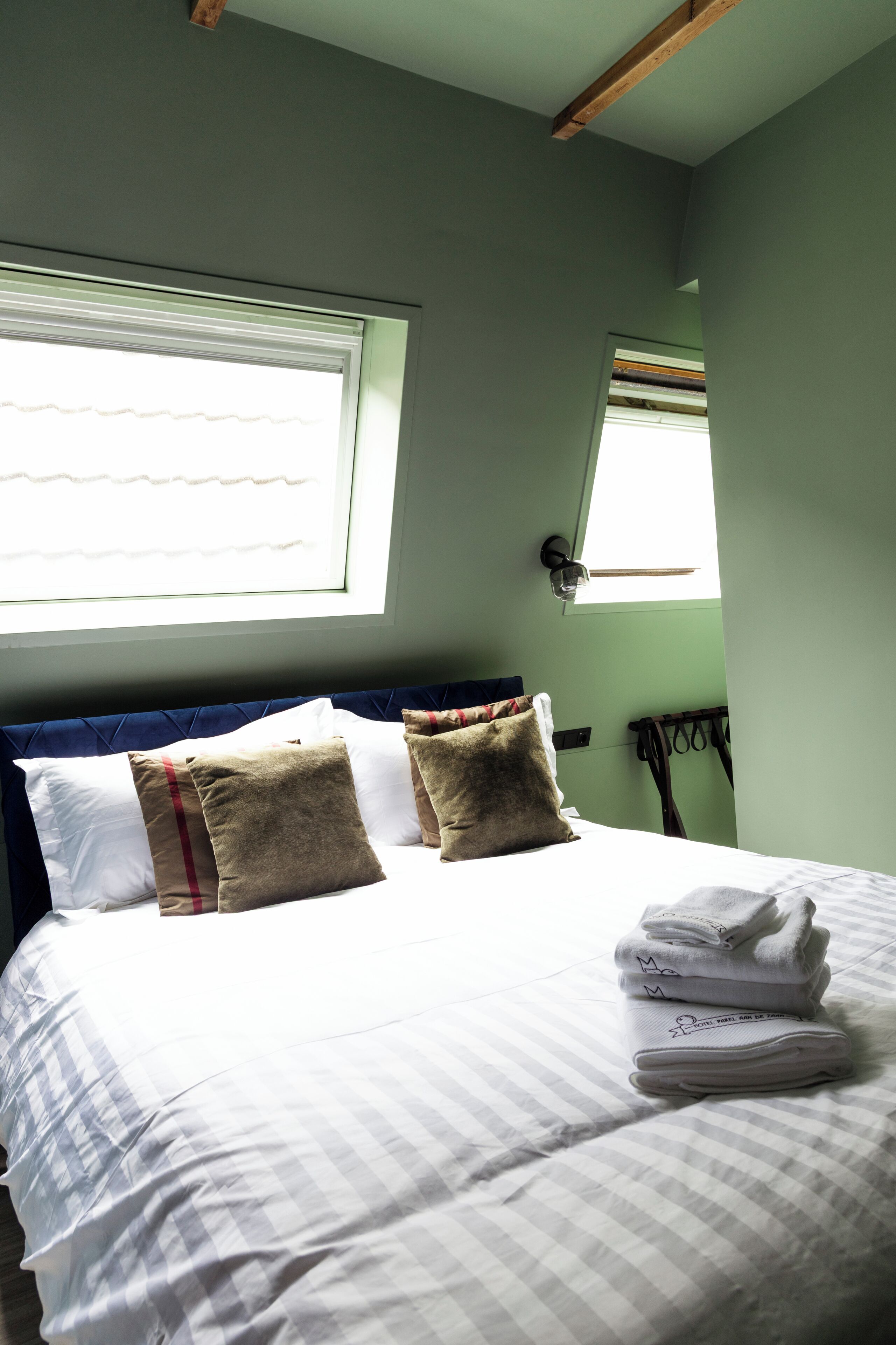 A neatly made bed with white and striped bedding, two pillows, and a stack of folded towels.