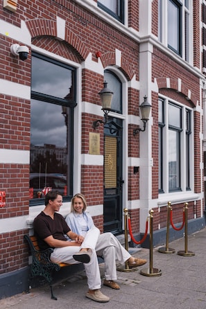 A bench outside a building with a brick facade and large windows.