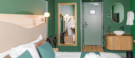 Una habitación de hotel con cama, baño, espejo y lavamanos.