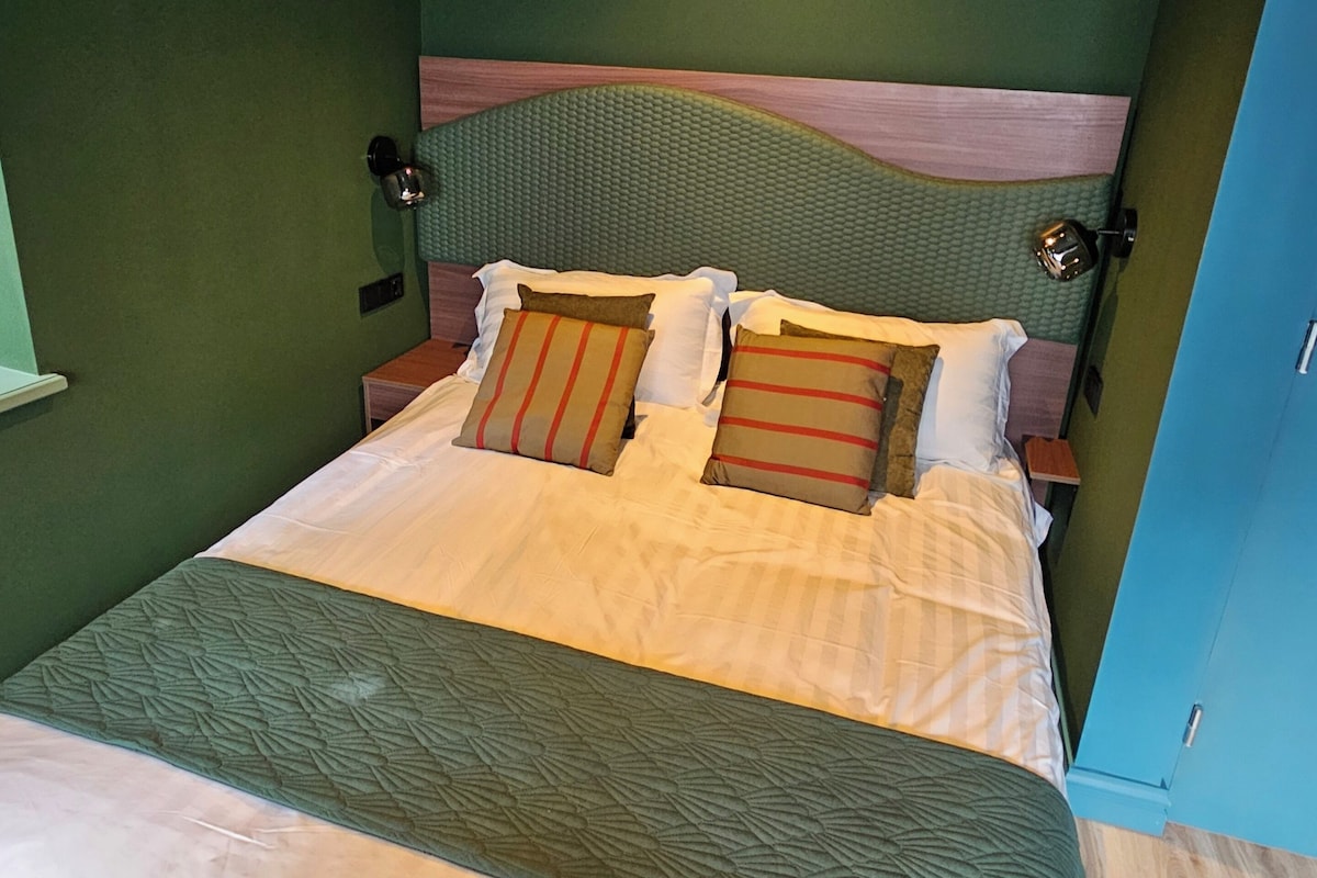 A bed with a headboard, pillows, and a blanket.
