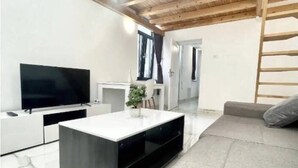 Un salon moderne avec un téléviseur à écran plat, une console blanche, un canapé gris et un plafond en bois.