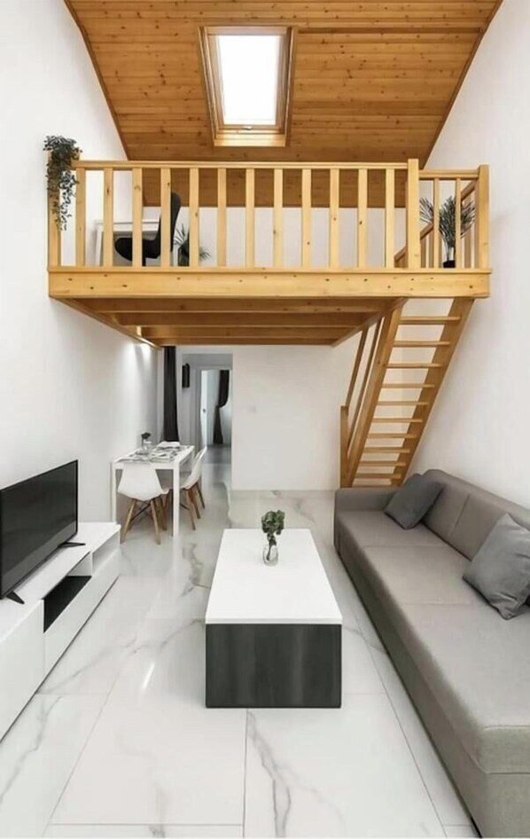 Quarto em estilo loft com varanda de madeira, área de refeições e sala de estar.