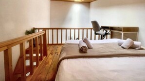 Une chambre avec un plafond en bois, un lit avec des oreillers, une chaise et un petit bureau.