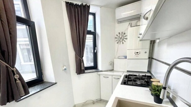 Une cuisine de taille réduite, équipée d’un évier, d’une cuisinière et de placards.