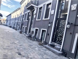 A row of buildings with a paved street, outdoor seating, and a cross on the door. - Skylit Loft Duplex in Historic Old Town Courtyard (București)
