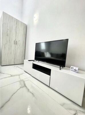 A modern living room with a flat-screen TV on a white entertainment unit, a marble floor, and a large wardrobe. - Skylit Loft Duplex in Historic Old Town Courtyard (București)