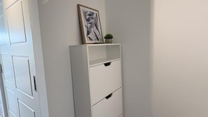 Une pièce d’angle avec un meuble blanc, une porte et une petite plante posée sur le dessus.