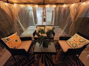 A covered outdoor seating area with a table and chairs, a potted plant, and a view of the interior. - Welcome to our beautiful centrally located home with a private conversation view (Lakeland)