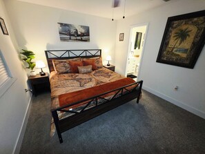 A bedroom with a bed, a nightstand, a lamp, a plant, and a painting on the wall. - Welcome to our beautiful centrally located home with a private conversation view (Lakeland)