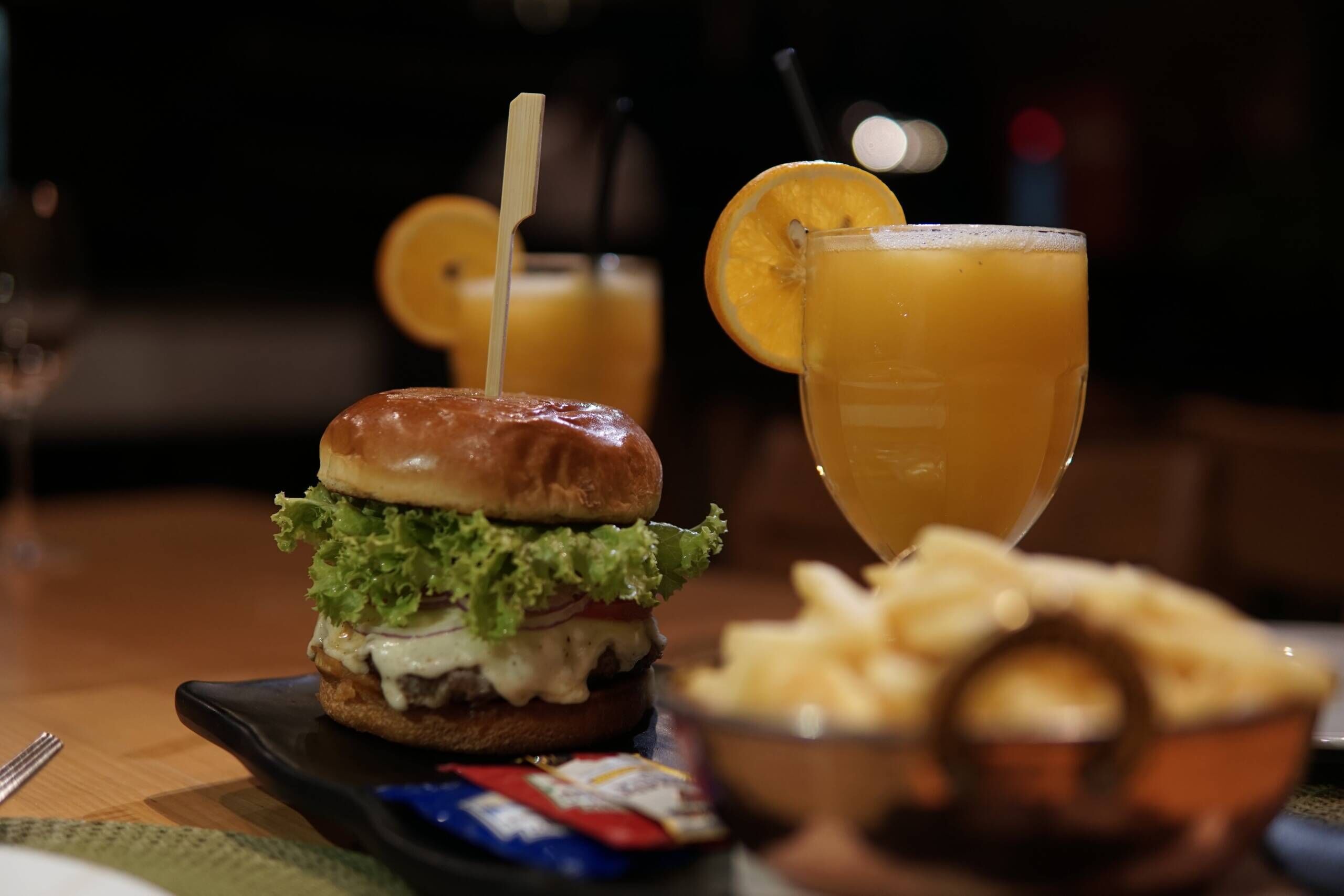 A meal consisting of a burger, a glass of orange juice, and a side of fries.