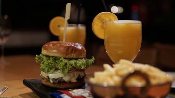 A meal consisting of a burger, a glass of orange juice, and a side of fries.