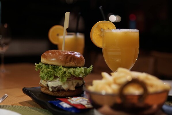 A meal consisting of a burger, a glass of orange juice, and a side of fries.