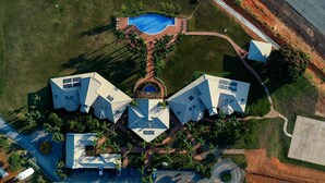 Vista aérea de un complejo residencial con varias casas, una piscina y un camino circular.