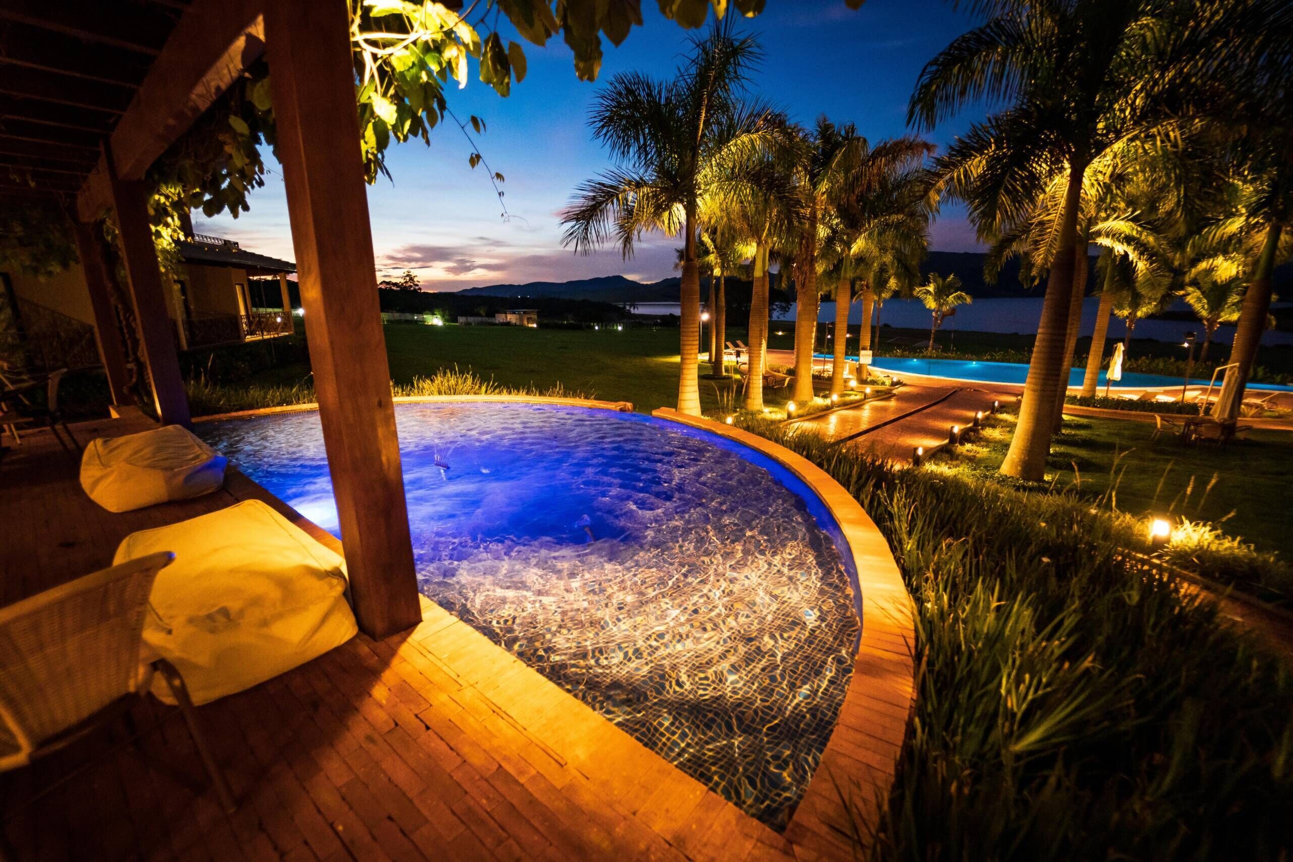 Een hottub omgeven door palmbomen en een zwembad, met uitzicht op de bergen.