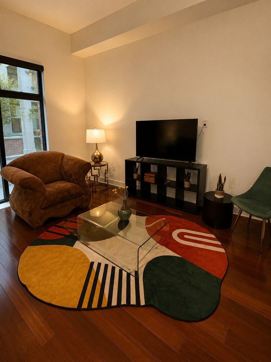 Een woonkamer met een bank, een televisie, een lamp, een salontafel en een vloerkleed.