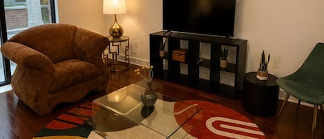 A living room with a sofa, a TV, a lamp, a coffee table, and a rug.