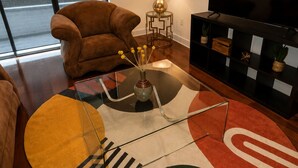 A living room with a sofa, a TV, a lamp, and a decorative rug. - Uptown Luxe ATL walk to Shops, Dining & MARTA (Atlanta)