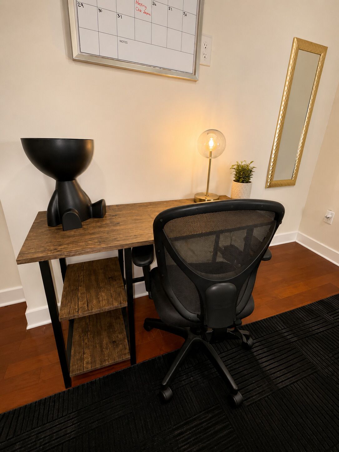 Un bureau avec une chaise, un calendrier, une lampe et un miroir.