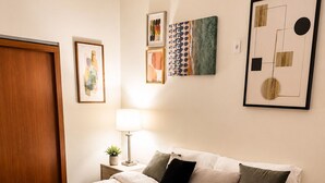 A neatly made bed with a white duvet, a bedside lamp, and a small plant on the nightstand. - Uptown Luxe ATL walk to Shops, Dining & MARTA (Atlanta)