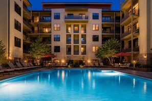 Ein mehrstöckiges Hotel mit Pool, Außenbereich und einer gut beleuchteten Fassade.