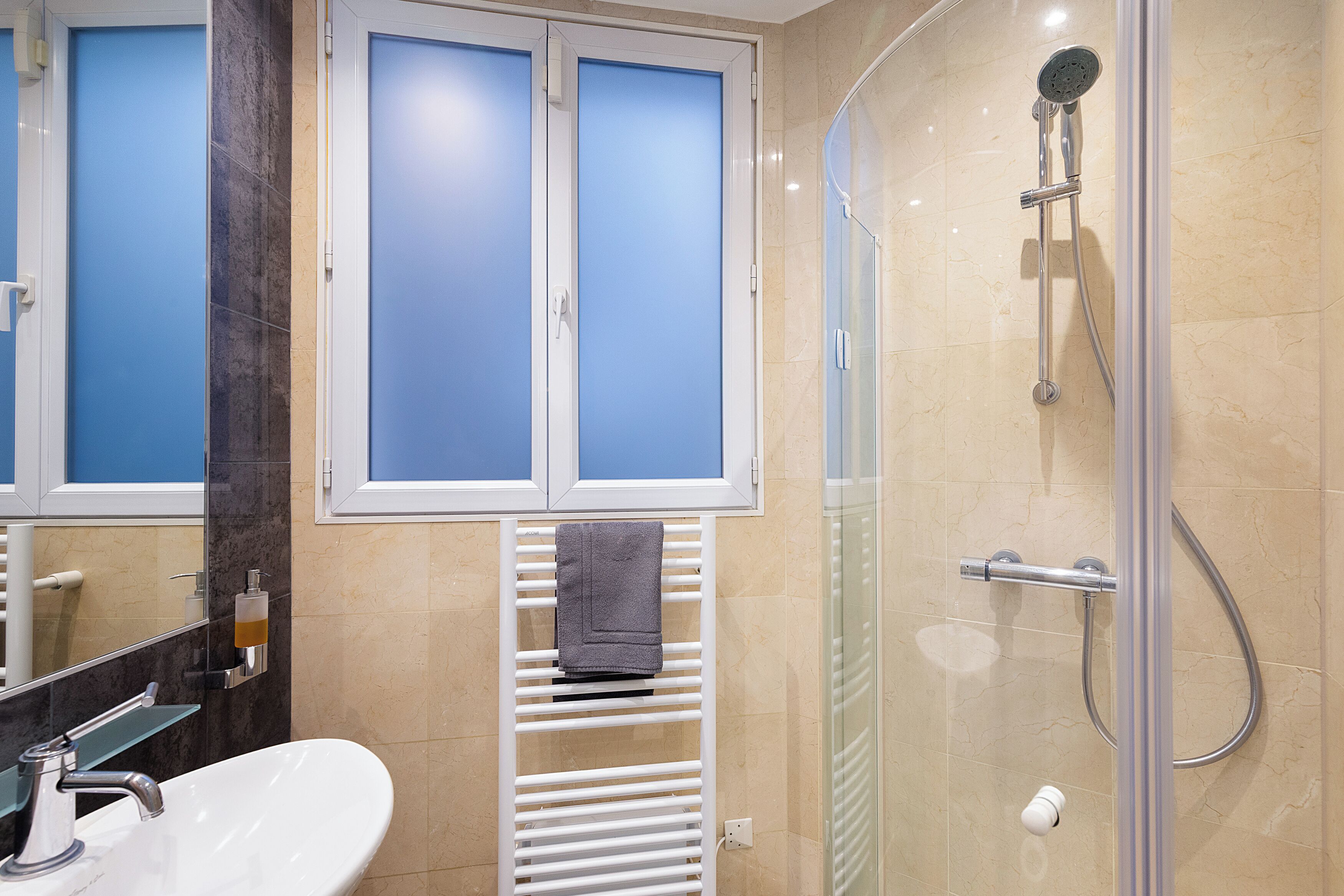 A bathroom with a shower, a sink, and a towel rack.