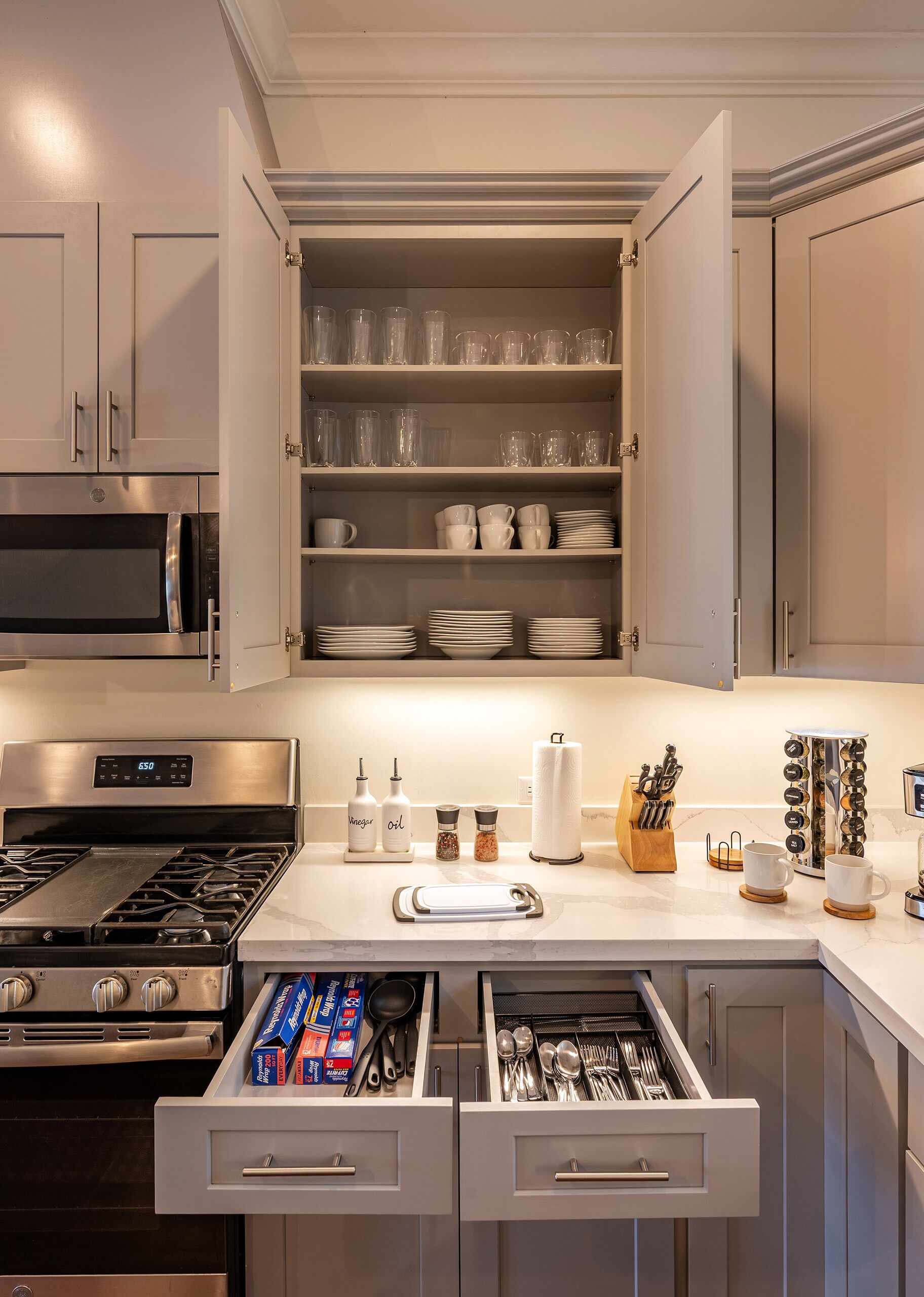 A kitchen with a built-in microwave, stainless steel appliances, and a pantry with glassware and dishes.