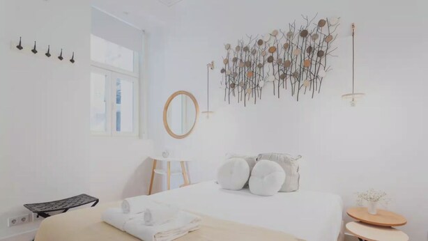 Une chambre à coucher au style minimaliste, avec un lit, une table de chevet et un miroir fixé au mur.