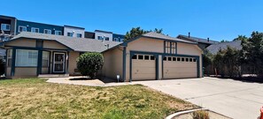 A residential building with a garage, a small front yard, and a clear blue sky. - Spacious Home , King Bed, Chef’s Kitchen Near UNR, Downtown & Convention Center (Reno)