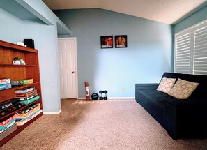 Ein Wohnzimmer mit Bücherregal, einer Couch und zwei gerahmten Sportpostern an der Wand.