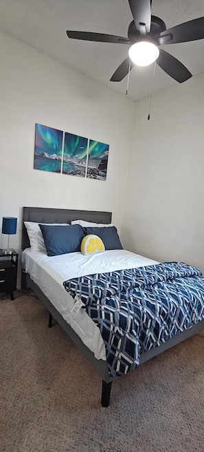 A bedroom with a bed, a nightstand, a lamp, a ceiling fan, and two wall-mounted pictures. - Spacious Home , King Bed, Chef’s Kitchen Near UNR, Downtown & Convention Center (Reno)