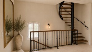 Un escalier avec une rampe en bois et des balustres noires, menant à l’étage supérieur.