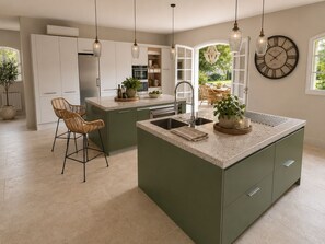 A modern kitchen with a central island, pendant lighting, and a large wall clock. - Luxury Provençal villa recently refurbished to an exceptional standard. (Fayence)