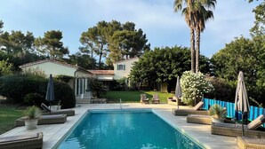Une piscine avec des chaises longues et une maison en arrière-plan.