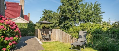 A backyard with a wooden fence, a patio table with chairs, and a lawn chair.