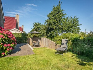 A backyard with a wooden fence, a patio table with chairs, and a lawn chair. - Spa Retreat With Private Sauna (De Koog)