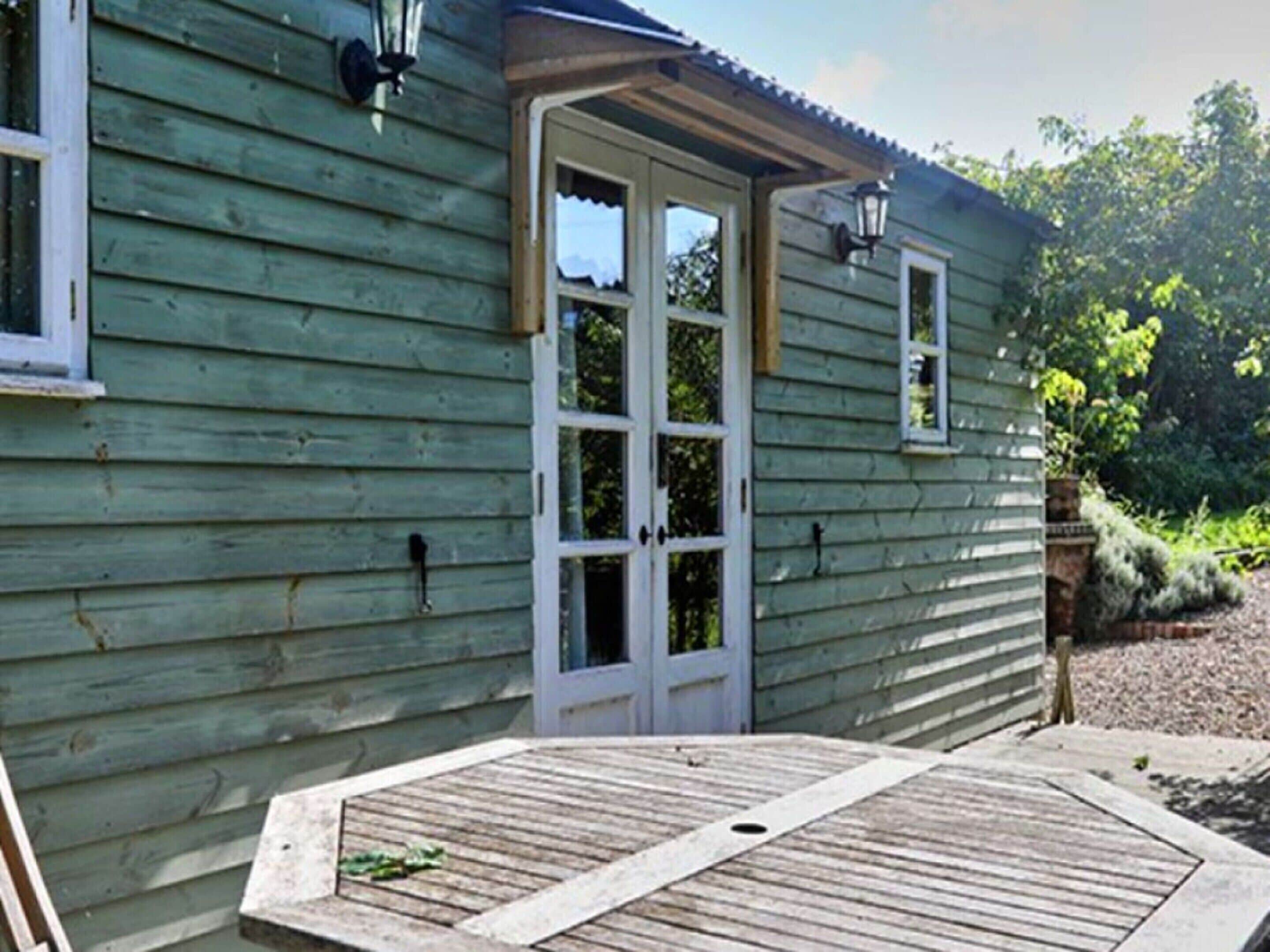 A wooden building with a door and windows, a porch, and a lamp post.