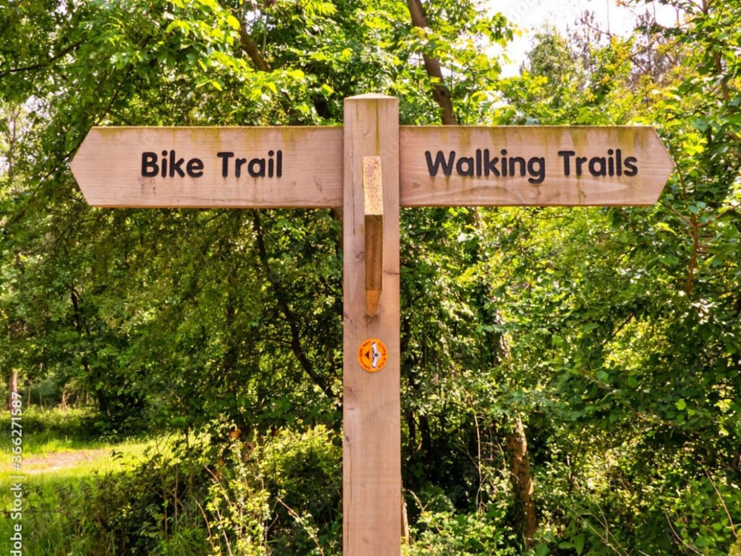 Un panneau indicateur en bois indiquant les directions pour une piste cyclable et des sentiers de randonnée.