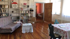 A cozy living room with a sofa, a table, and bookshelves filled with books.