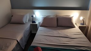A double room with two beds, each with a nightstand and a lamp.