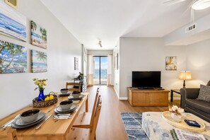 A modern living room with a dining area, a flat-screen TV, and artwork on the walls. - Oceanfront Bliss, Top Floor, 2BR, Indoor Pool & Hot Tub, Free Parking, Elevators (North Myrtle Beach)