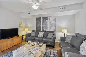 A living room with a sofa, a coffee table, a TV, and artwork on the wall. - Oceanfront Bliss, Top Floor, 2BR, Indoor Pool & Hot Tub, Free Parking, Elevators (North Myrtle Beach)