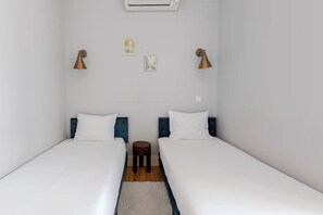 A room with two beds, a small round table, and two wall-mounted lamps. - Pombal-Style House - 2BR/2Bath - AC - Blue Tiles (Lisboa)