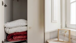 Un armario con ropa de cama blanca y roja, un marco de madera para un cuadro y una ventana con vistas.