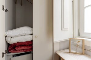 A closet with white and red bedding, a wooden-framed picture frame, and a window with a view. - Pombal-Style House - 2BR/2Bath - AC - Blue Tiles (Lisboa)