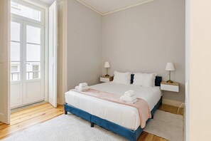 A bedroom with a bed, two bedside tables, a door, and a window. - Pombal-Style House - 2BR/2Bath - AC - Blue Tiles (Lisboa)