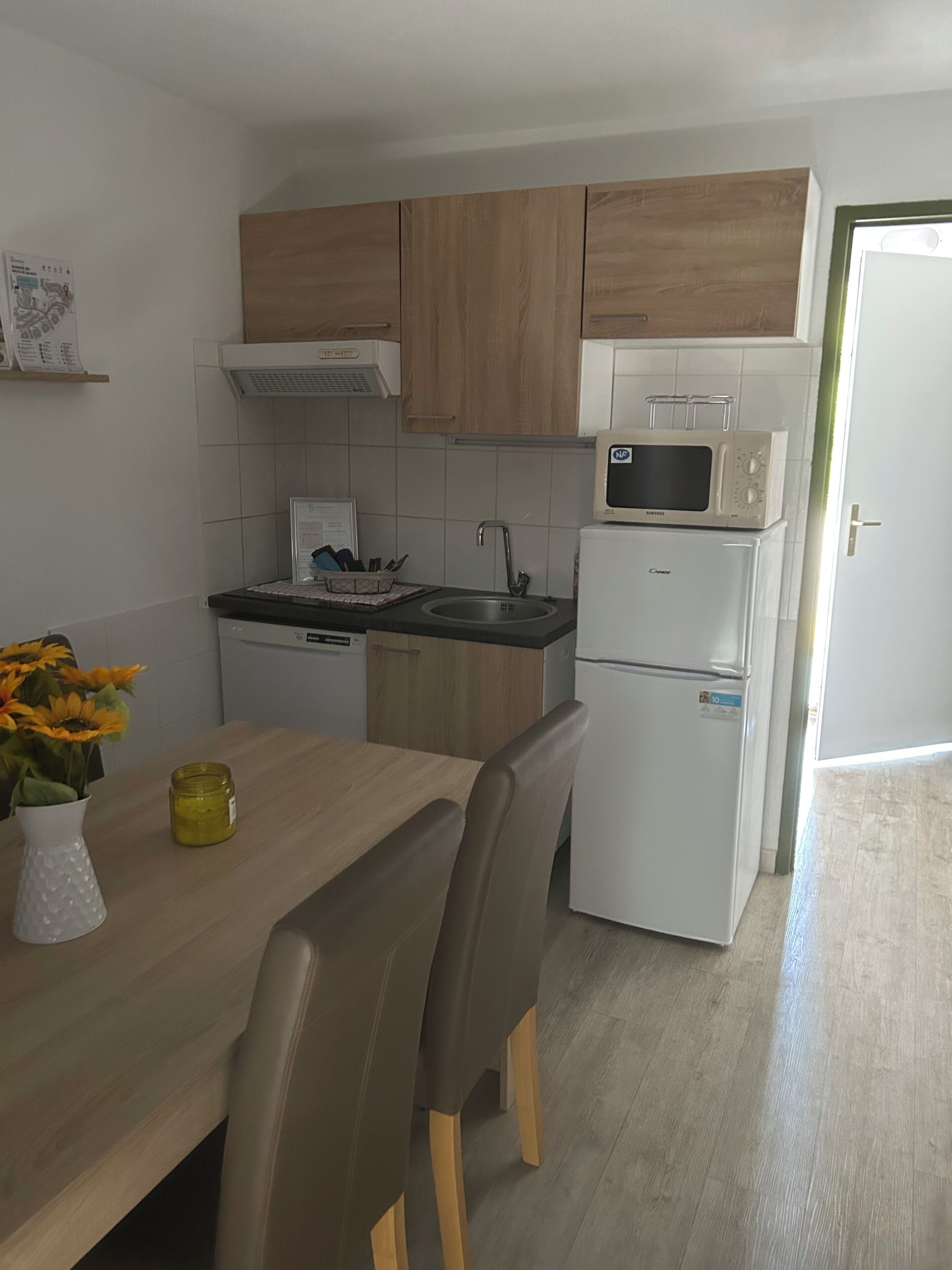 Une cuisine de taille réduite, dotée de meubles en bois, d’un four à micro-ondes, d’un évier et d’un réfrigérateur.